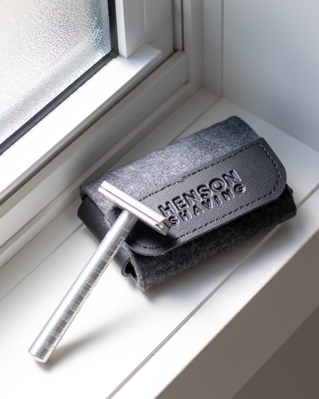 The Henson Razor and Henson Travel Case on a window sill